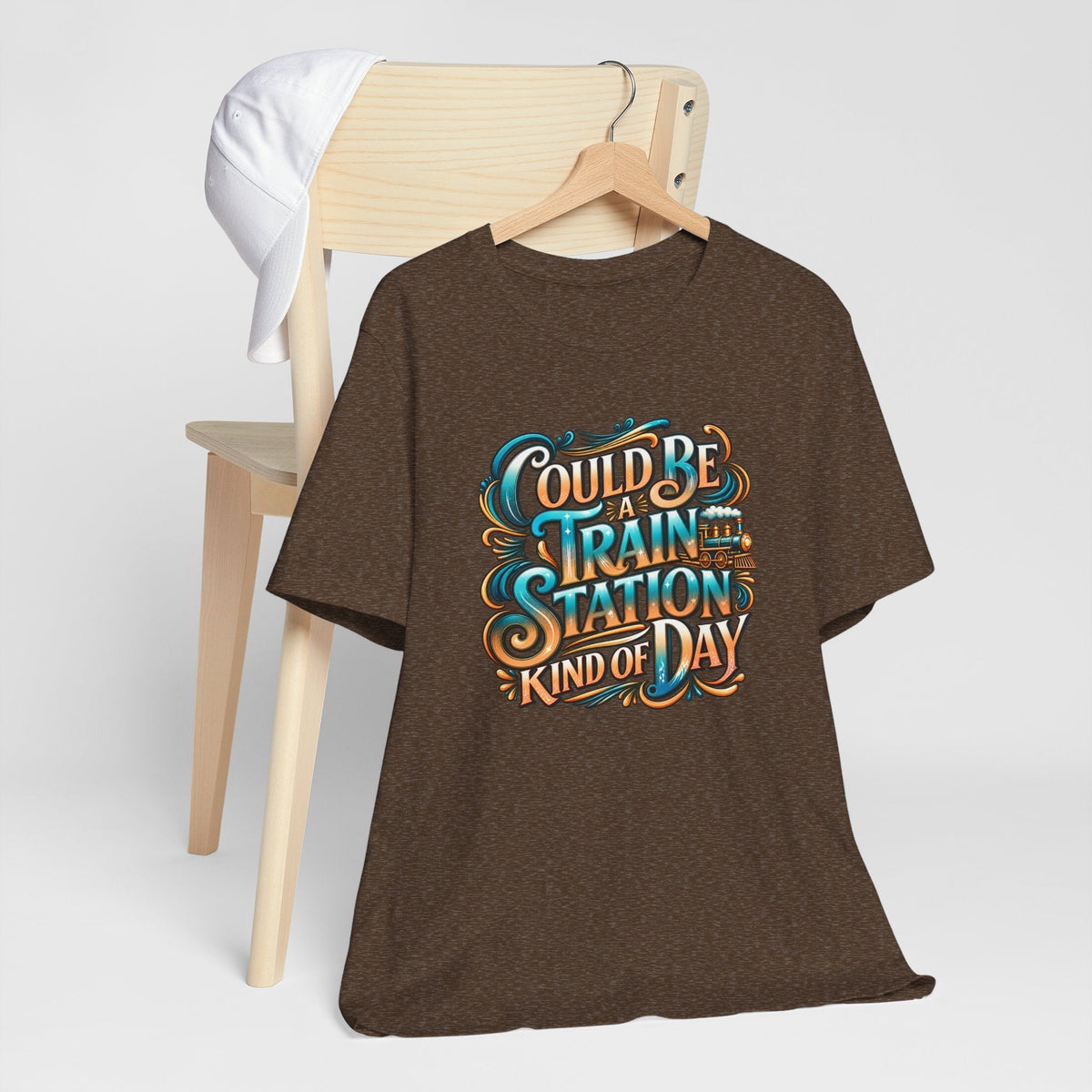 T-shirt in dark brown heathered fabric with ornate turquoise and orange train station kinda day lettering and train graphic
