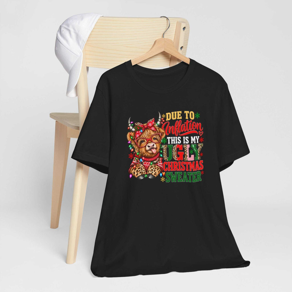 ugly christmas shirt in black cotton with a colorful Highland cow, festive lights and humorous holiday lettering