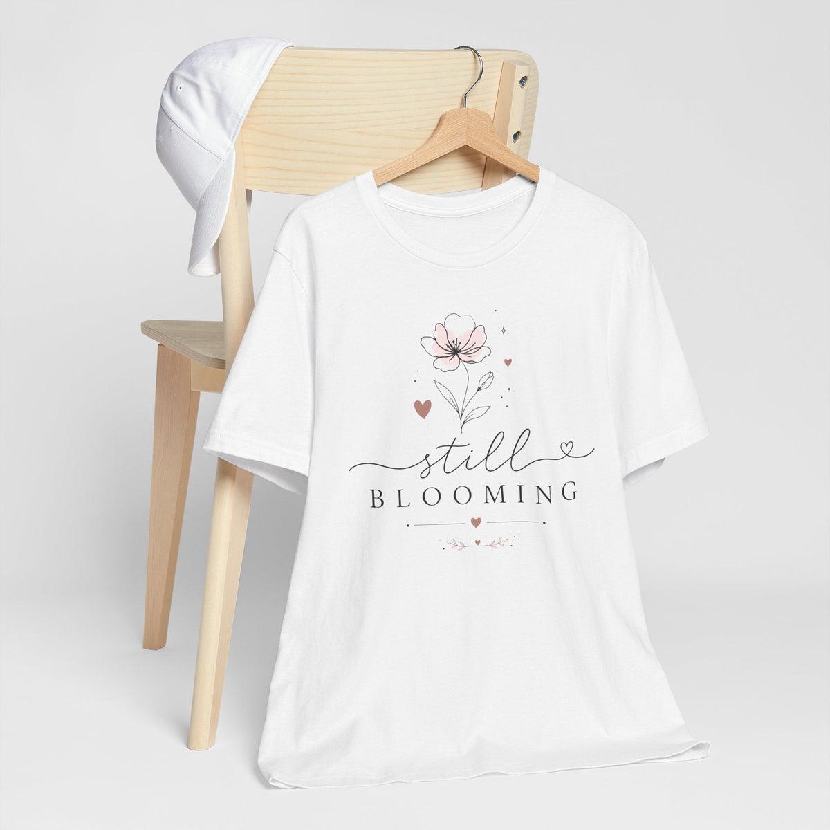 Women's inspirational tshirts: white cotton tee with delicate blush floral artwork, script “Still Blooming” text and heart accents