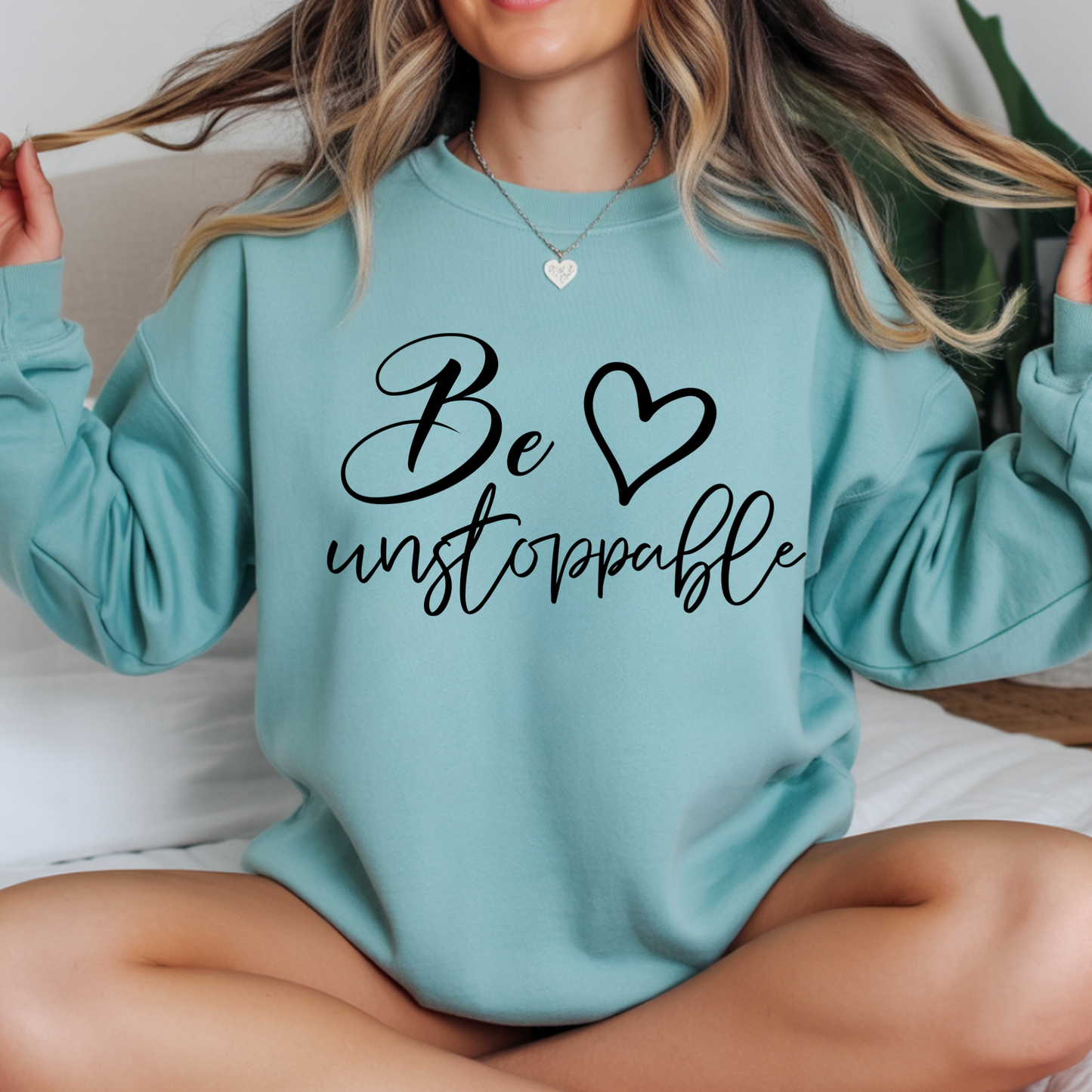 Person wearing a light blue sweatshirt with 'Be unstoppable' text 